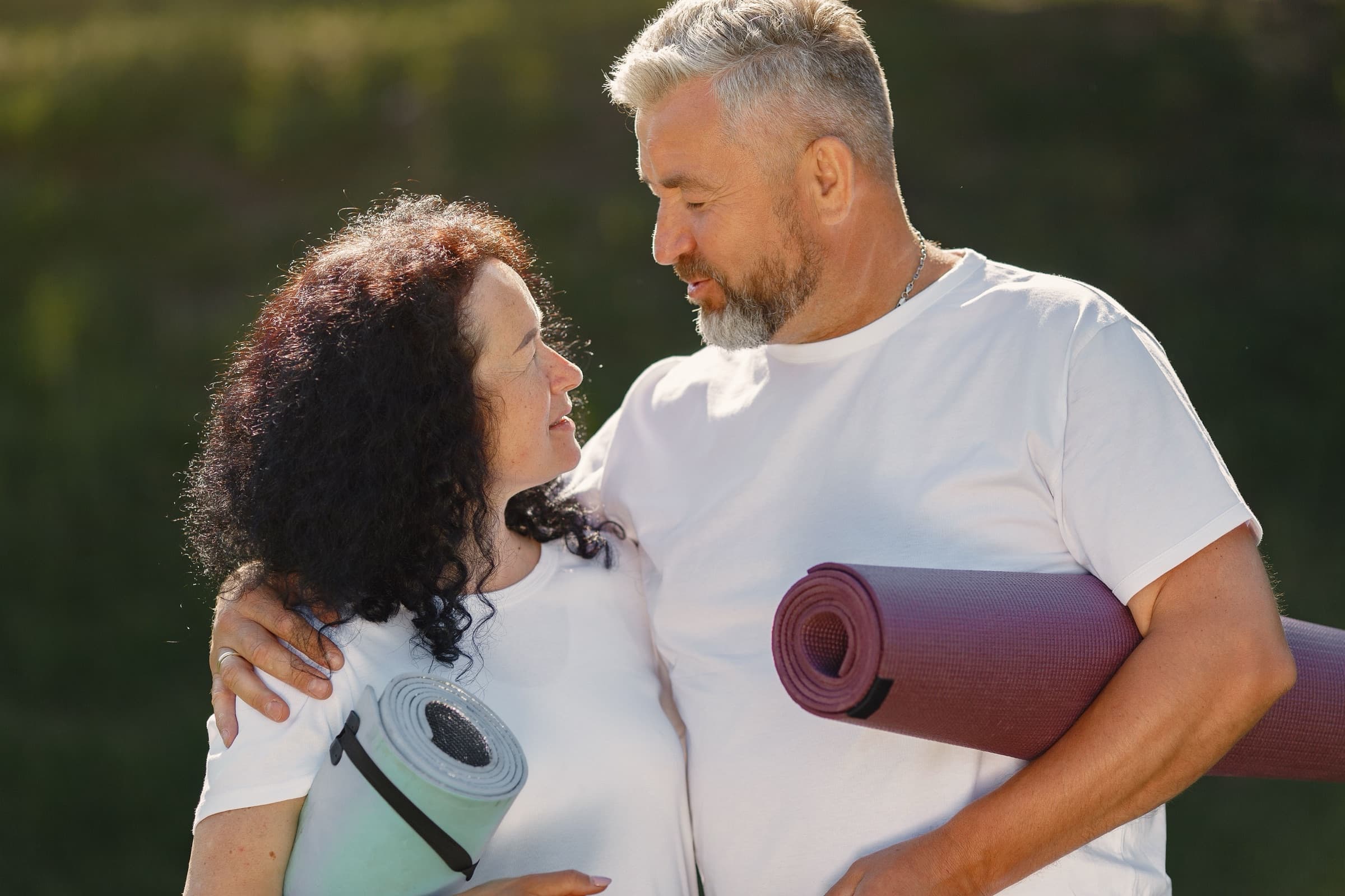 Couple souriant tenant des tapis de yoga, patients Vision Laser Genève